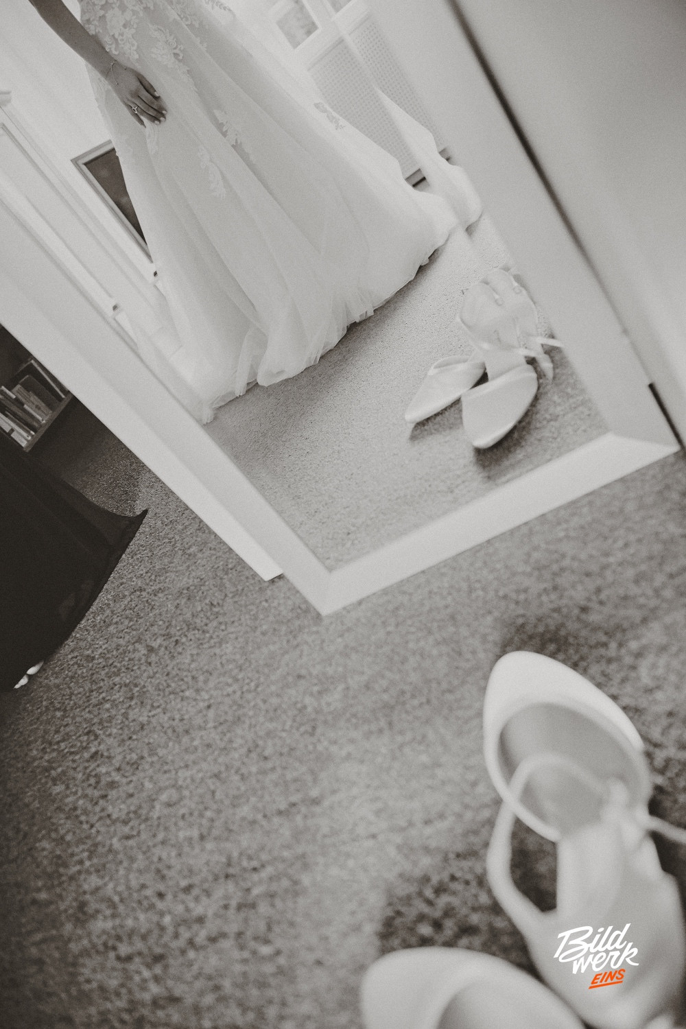 Foto: Copyright - Paul Walther - Die Braut beim Ankleiden bei sich zu Hause. Sie steht vor dem Spiegel und betrachtet sich. Es ist nur ein Ausschnitt, auf dem im Vordergrund die Brautschuhe stehen.